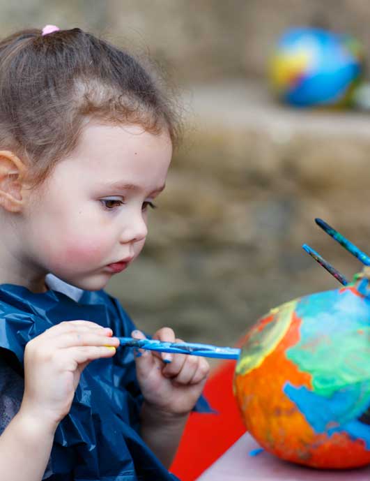 girl painting a pumpkin for halloween